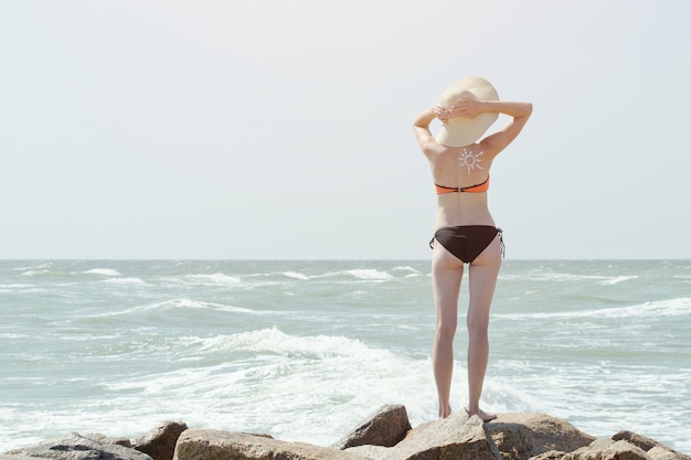 Vrouw in een hoed en een zwempak aan zee. Achteraanzicht.