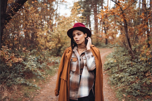 Vrouw in een hoed en jas in het bos