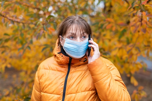 Vrouw in een medisch masker loopt in het herfstpark