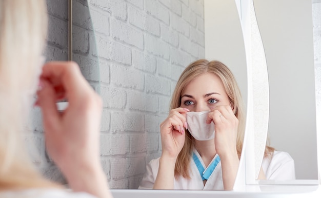 Vrouw in een medisch masker voor een spiegel