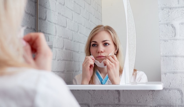 Vrouw in een medisch masker voor een spiegel