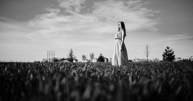 Vrouw in een mooie lange turkooizen jurk die zich voordeed op een weide op gras