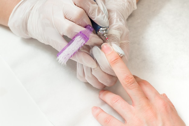 Vrouw in een nagelsalon een manicure ontvangen door een schoonheidsspecialiste met nagelvijl schoonheid en handverzorging