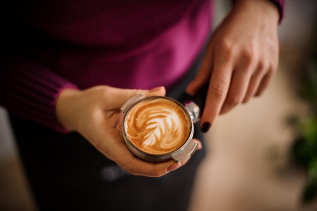 Vrouw in een paars shirt met een bui met een mooi latte-art
