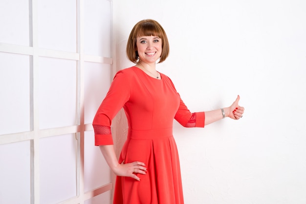 Vrouw in een rode jurk poseren binnenshuis