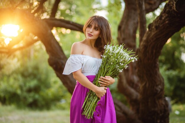 Vrouw in een romantische zonsondergang met een boeket bloemen