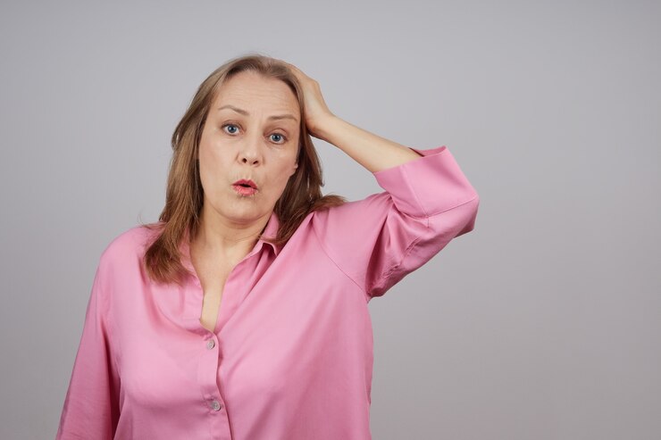 vrouw in een roze shirt met haar hand tegen haar hoofd