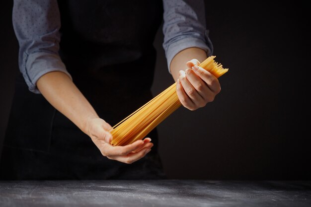 Vrouw in een schort met een bos rauwe spaghetti