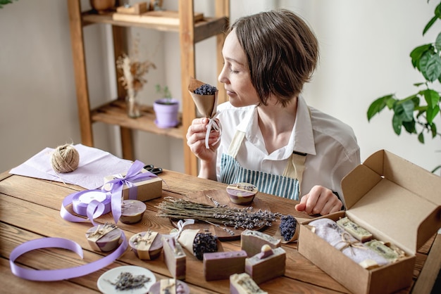 Vrouw in een schort pakt natuurlijke lavendelzeep in en decoreert het met lavendelbloemen Concept van natuurlijke zeep en handgemaakte geschenken