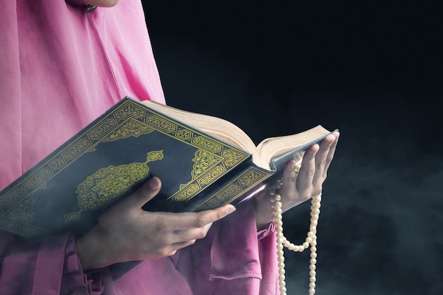 vrouw in een sluier met gebedskralen en de koran