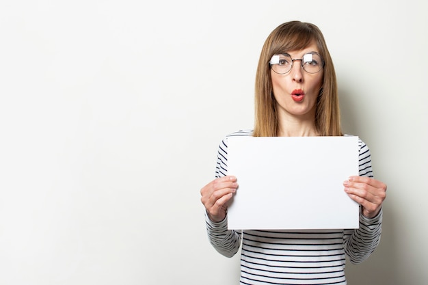 Vrouw in een trui en een bril met een blanco vel papier