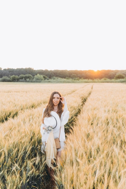 vrouw in een witte jurk en een witte hoed in een tarweveld