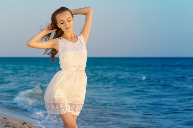 Vrouw in een witte jurk op strand