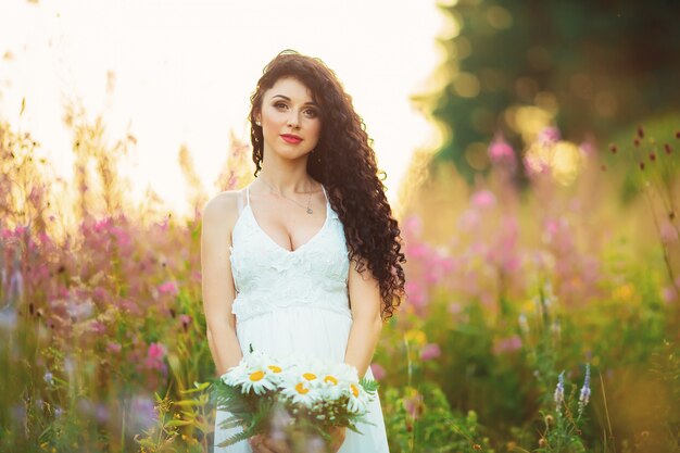 Vrouw in een witte jurk poseren in een veld