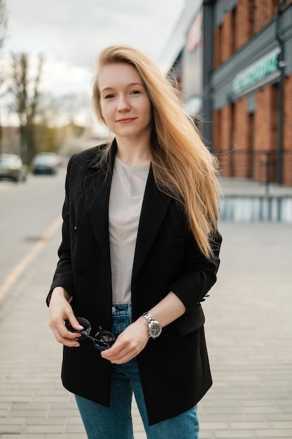 Vrouw in een zwarte jas met zonnebril op straat