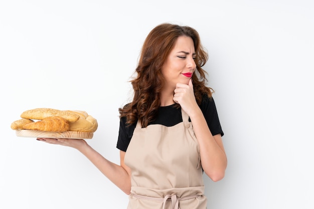 Vrouw in eenvormige chef-kok. vrouwelijke bakker die een lijst met verscheidene broden houden die een idee denken en kant kijken