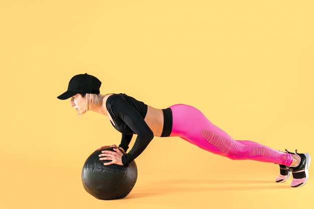 Vrouw in fitness kleding training met een medicijnbal. Vrouwelijke atleet die buiktraining doet die een geneeskundebal gebruikt.