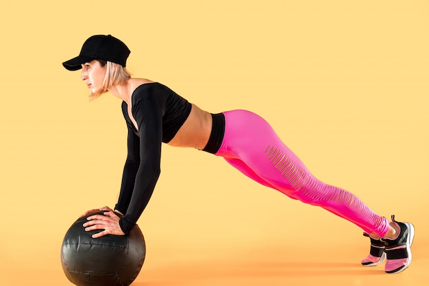 Vrouw in fitness kleding training met een medicijnbal. Vrouwelijke atleet die buiktraining doet die een geneeskundebal gebruikt.