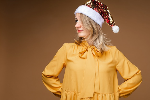 Vrouw in gele kleding met blond haar dat een voorwerp achter zichzelf verbergt en naar de zijkant kijkt. nieuwjaar concept