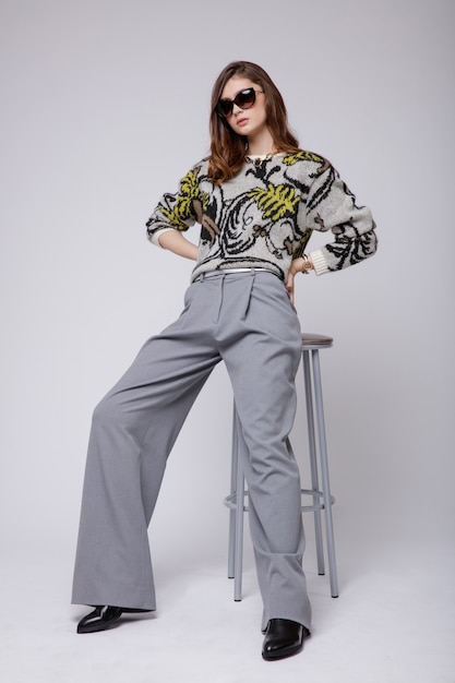 Vrouw in grijze broek blouse bicolor accessoires laarzen op witte achtergrond Bruin haar Studio Shot