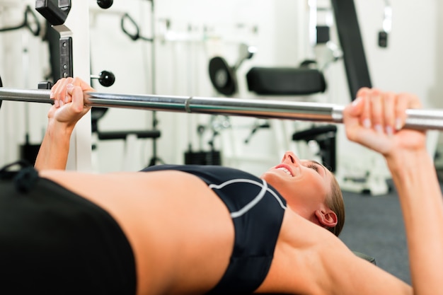 Vrouw in gymnastiek die met barbell uitoefenen