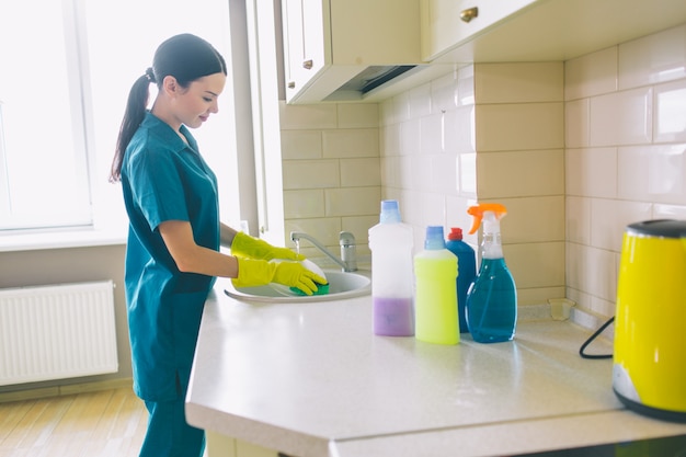 Vrouw in handschoenen die de keuken schoonmaken