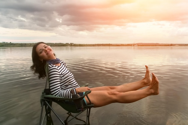 Vrouw in het gestreepte shirt zit op een stoel in het water Toned