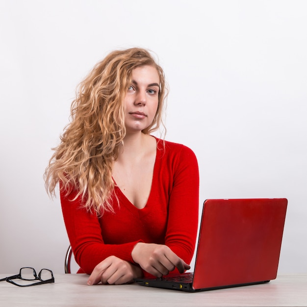 Vrouw in het rood, op afstand werken op de computer op wit.