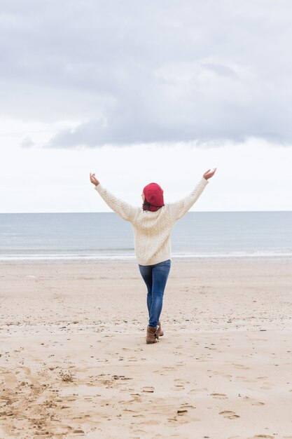 Vrouw in het toevallige warme slijtage uitrekkende wapens op strand