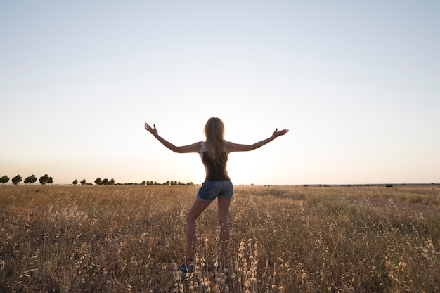 Vrouw in het veld voor een zonsondergang