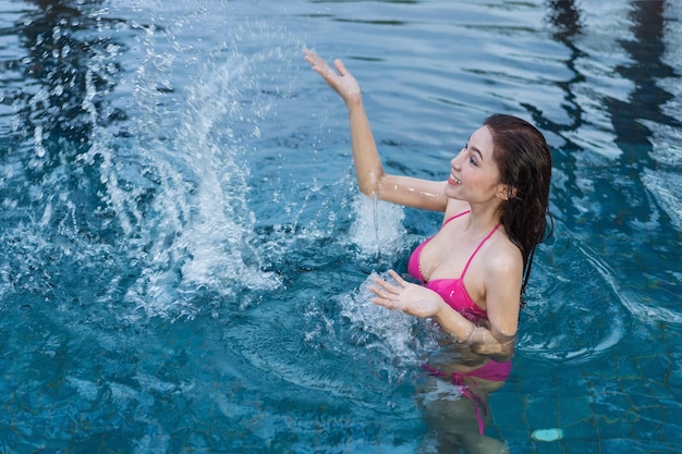 vrouw in het zwembad en het spelen van water splash