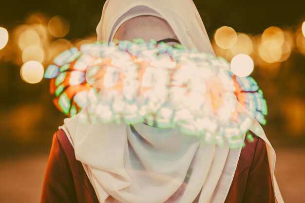 Foto vrouw in hijab gezien door glas met reflectie van kleurrijke lichten