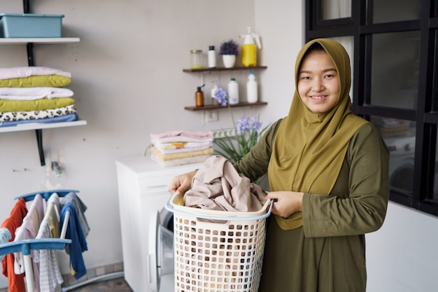 Vrouw in hijab thuis kleding wassen met behulp van wasmachine