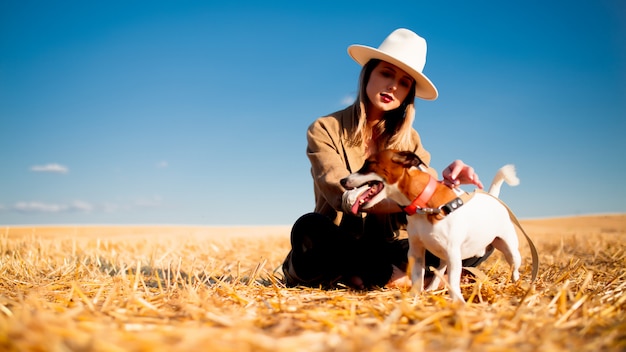 Vrouw in hoed met hond op veld