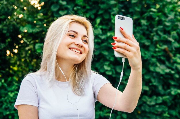 Vrouw in hoofdtelefoons en smartphone in handen die op groene achtergrond zitten