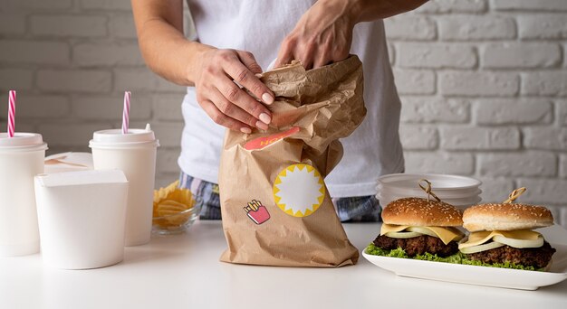 Vrouw in huiskleding die eten thuisbezorgt met hamburgers, noedeldozen en drankjes