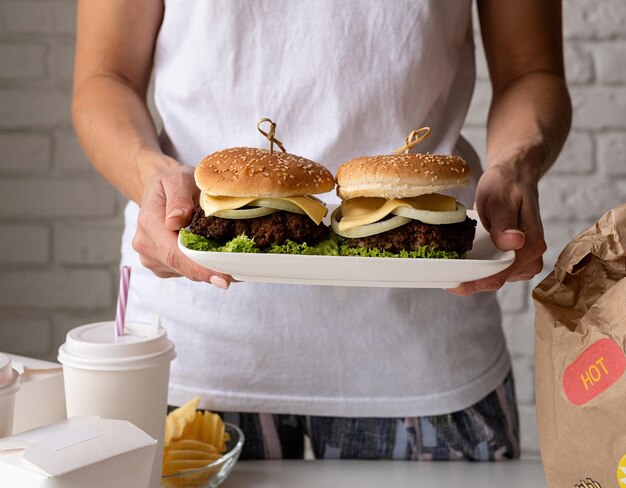 Foto vrouw in huiskleding die eten uitpakt met thuisbezorging met burgers, noedels en dranken.