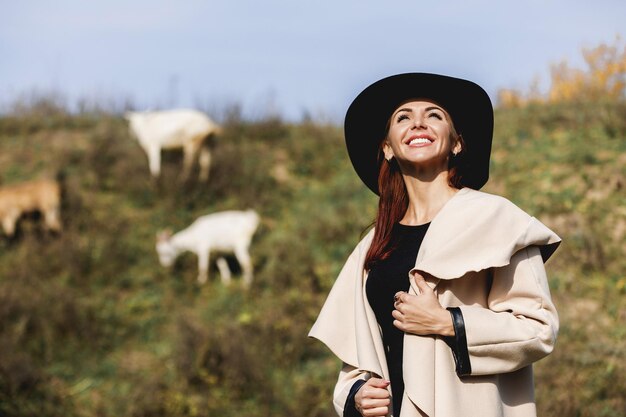 Vrouw in jas en hoed op zonnige herfstdag