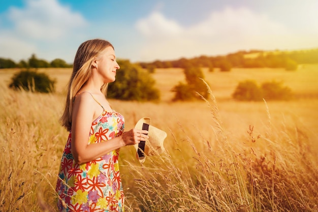 Vrouw in jurk en hoed wandelen in een tarweveld in de zomer