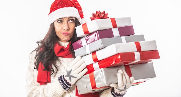 Vrouw in kerstkleren houdt een stapel ingepakte cadeautjes vast en denkt aan wat ze is vergeten.