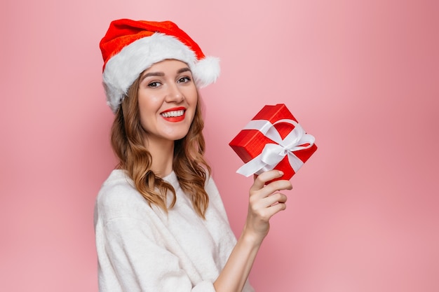 vrouw in Kerstman hoed glimlachend en rode geschenkdoos te houden