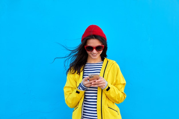 Vrouw in kleurrijke outfit met smartphone blauwe achtergrond