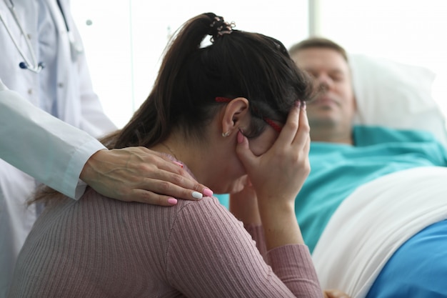 Vrouw in kliniek die dichtbij de mens in het ziekenhuisbed schreeuwt