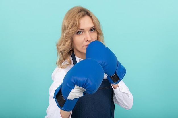 Vrouw in kok schort bokshandschoenen ponsen, knock-out.