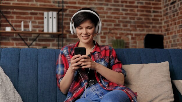Vrouw in koptelefoon luisteren muziek op slimme telefoon met behulp van muziek-app. Ontspanning, vrije tijd.