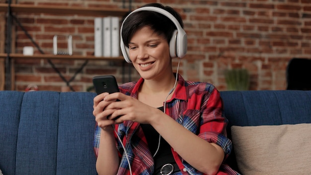 Vrouw in koptelefoon luisteren muziek op slimme telefoon met behulp van muziek-app. Ontspanning, vrije tijd.