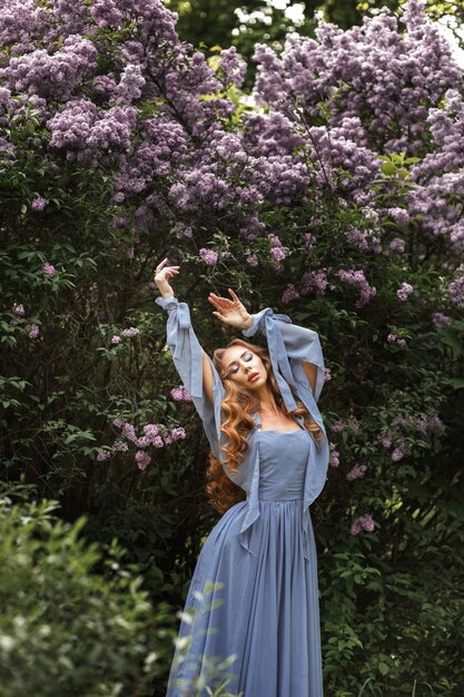 Vrouw in lange jurk naast sering in de tuin in de zomer voor een wandeling