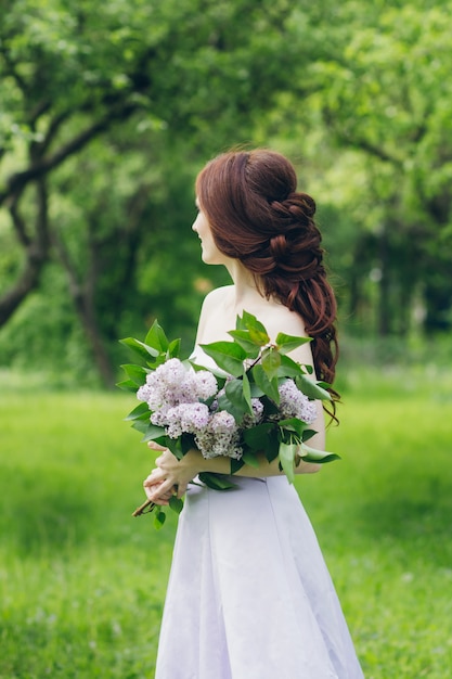 Vrouw in lange witte jurk in zomertuin