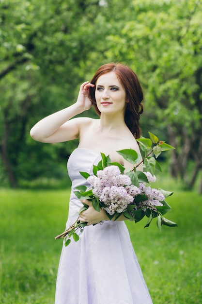 Vrouw in lange witte jurk in zomertuin