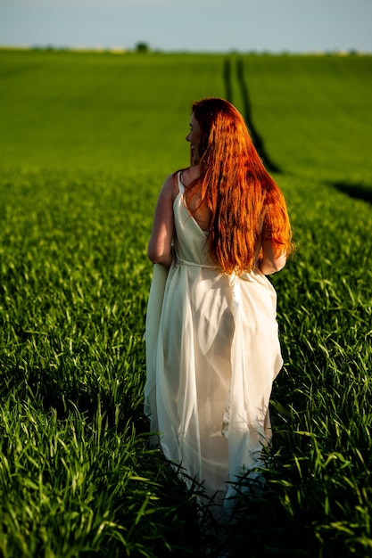 Vrouw in lange witte jurk op een groen veld